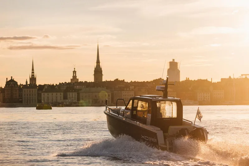 Slide: The Image of XO DFNDR 9 boat cruising at sunset near city skyline, 2027 model. - 11