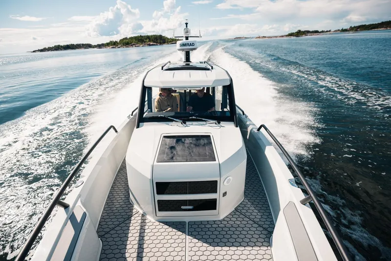 Slide: The Image of 2027 XO DFNDR 9 boat cruising on open water under a clear sky. - 13
