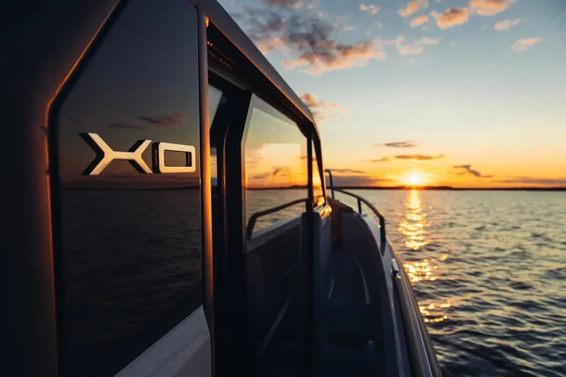 Slide: The Image of 2027 XO DFNDR 9 boat cruising at sunset on open water. - 19