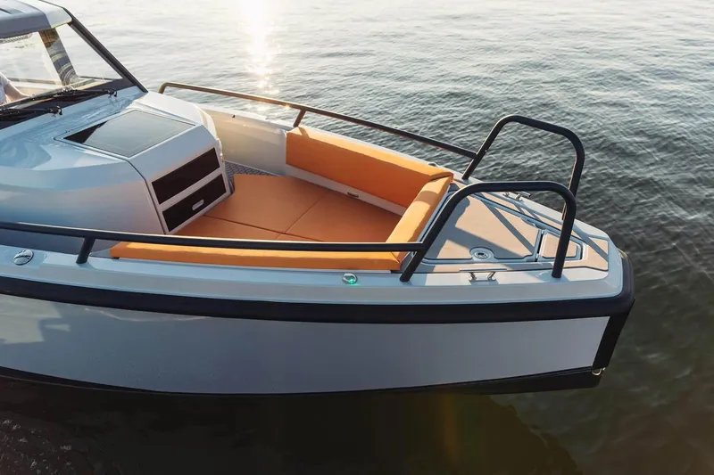 Slide: The Image of 2027 XO DFNDR 9 boat with orange seating, docked on calm water. - 22