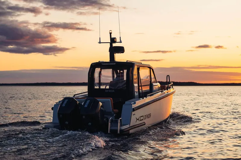 Slide: The Image of 2027 XO DFNDR 9 boat cruising at sunset on open water. - 6