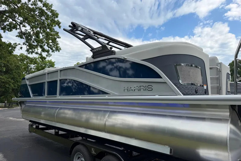 Slide: The Image of 2026 Harris Grand Mariner 250 CWDH pontoon boat on trailer, under a partly cloudy sky. - 3