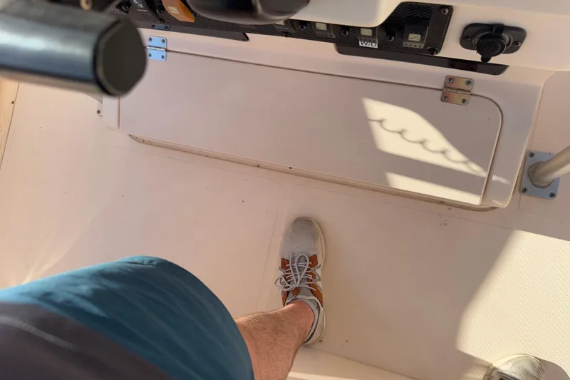 Slide: The Image of Person standing on a 2007 Grady-White Escape 209 boat deck, wearing sneakers and shorts. - 18