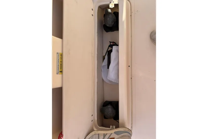 Slide: The Image of Storage compartment in a 2007 Grady-White Escape 209 boat, containing life jackets and equipment. - 24