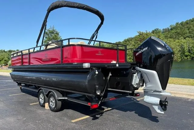 Slide: The Image of 2025 Regency 250 DL3 pontoon boat with Mercury outboard, parked near a lake. - 10