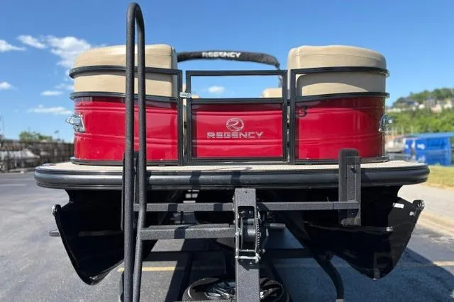 Slide: The Image of 2025 Regency 250 DL3 pontoon boat, red exterior, parked on a trailer under a clear sky. - 11