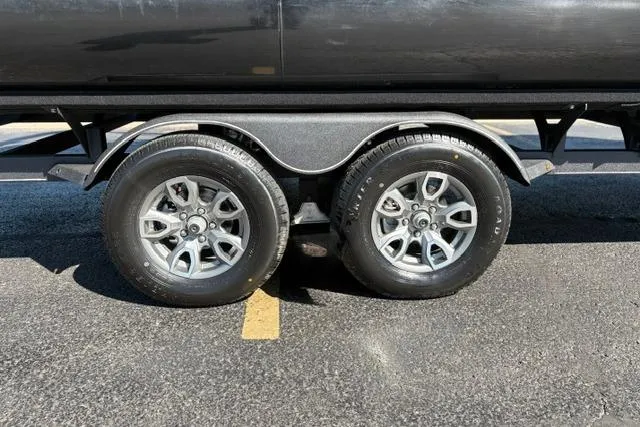 Slide: The Image of 2025 Regency 250 DL3 trailer wheels on asphalt, showcasing dual axle design. - 14