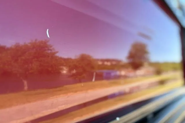 Slide: The Image of Reflection on 2025 Regency 250 DL3 boat surface, showing trees and sky. - 24