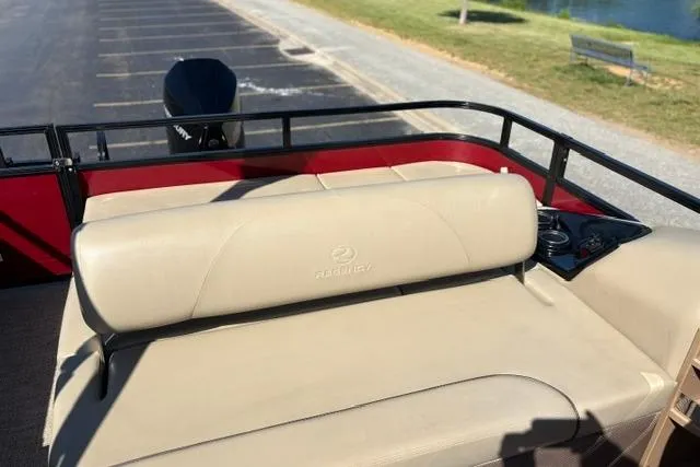 Slide: The Image of 2025 Regency 250 DL3 boat with beige seating and rear motor, parked near a lake. - 32