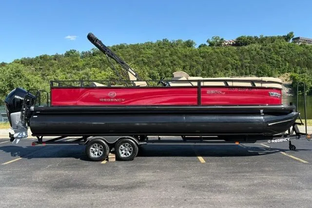 Slide: The Image of 2025 Regency 250 DL3 pontoon boat on trailer, parked outdoors with scenic background. - 4
