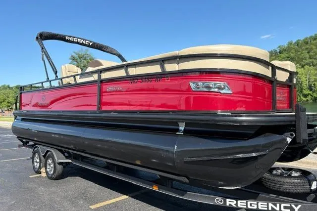 Slide: The Image of 2025 Regency 250 DL3 pontoon boat with red and black design on a trailer. - 7