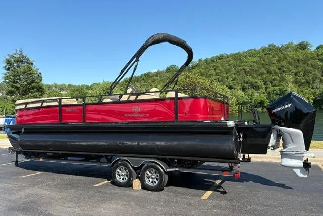 Slide: The Image of 2025 Regency 250 DL3 pontoon boat with Mercury engine on trailer, parked outdoors. - 9
