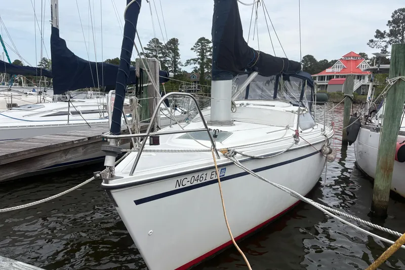 The Image of 1989 Hunter Vision 32 sailboat docked at marina with surrounding boats and trees. - 0