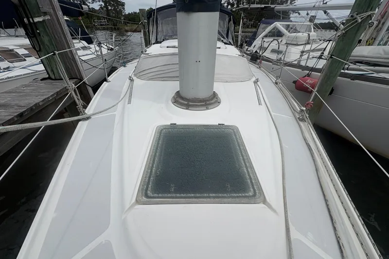 Slide: The Image of 1989 Hunter Vision 32 sailboat deck view at marina, featuring ropes and hatch. - 10