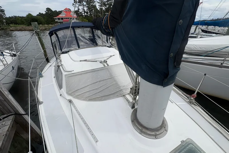 Slide: The Image of 1989 Hunter Vision 32 sailboat docked, featuring a covered mast and spacious deck. - 13