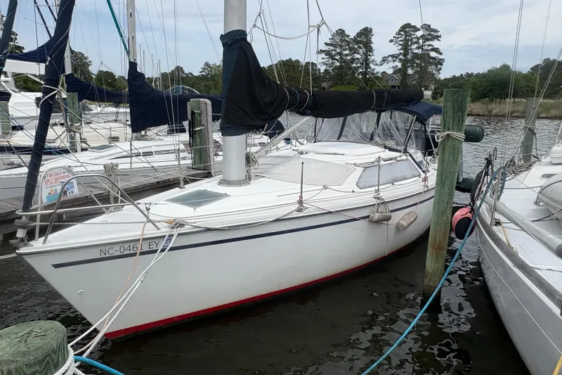 Slide: The Image of 1989 Hunter Vision 32 sailboat docked at marina, featuring sleek design and covered cockpit. - 2