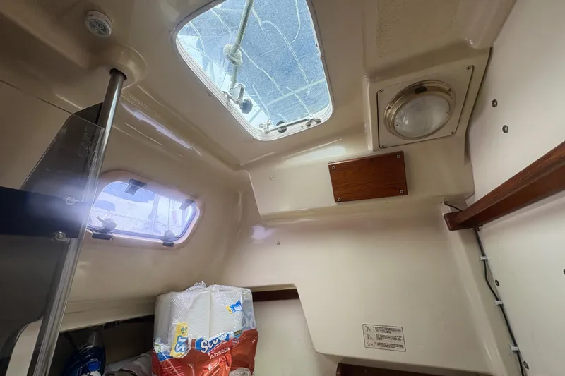 Slide: The Image of Interior cabin view of a 1989 Hunter Vision 32 sailboat, featuring a skylight and storage area. - 55