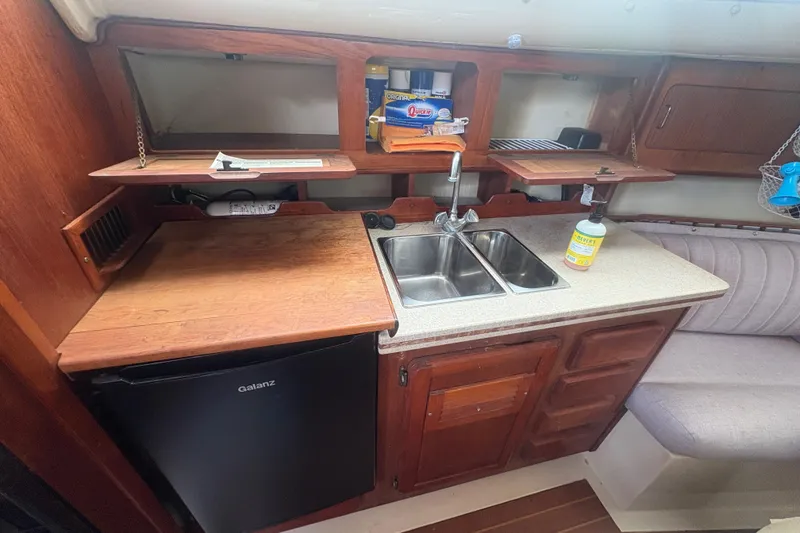 Slide: The Image of 1989 Hunter Vision 32 yacht kitchen with sink, wooden cabinets, and compact fridge. - 57