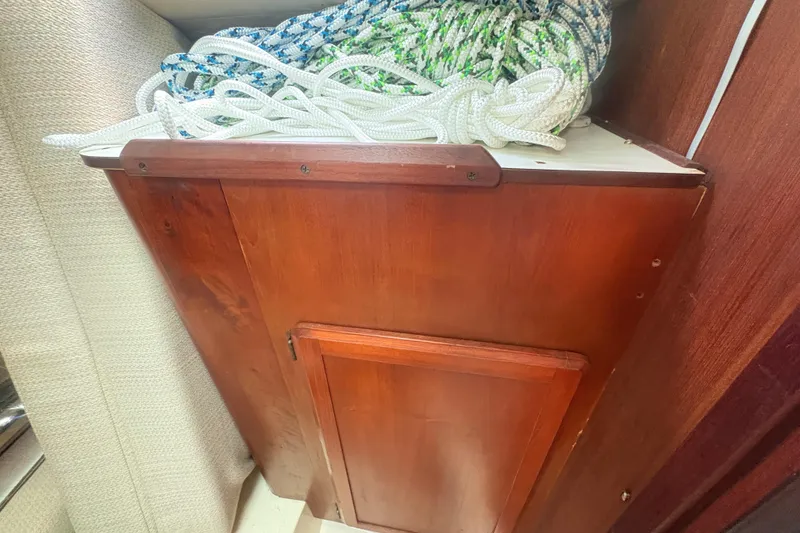 Slide: The Image of Wooden cabinet with coiled ropes on a 1989 Hunter Vision 32 sailboat. - 74