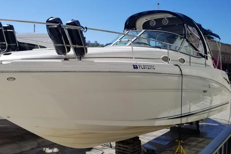 The Image of 2004 Sea Ray 300 Sundancer boat on dry dock, white hull, blue canopy. - 1
