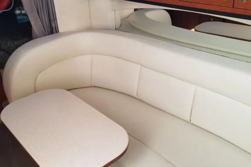 Slide: The Image of 2004 Sea Ray 300 Sundancer interior with cream leather seating and a compact table. - 11