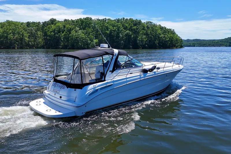 Slide: The Image of 2003 Sea Ray 380 Sundancer cruising on a scenic lake under a clear blue sky. - 10