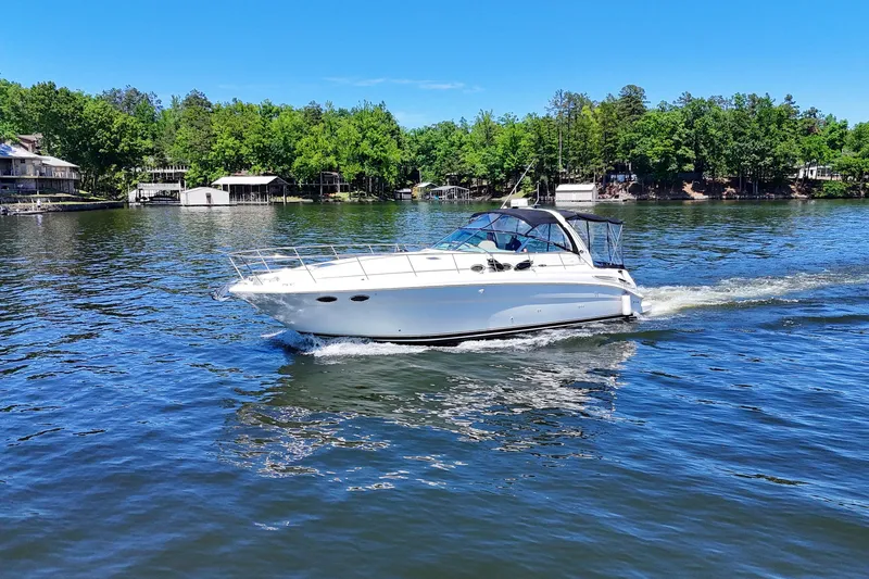 Slide: The Image of 2003 Sea Ray 380 Sundancer cruising on a serene lake with lush green shoreline. - 11