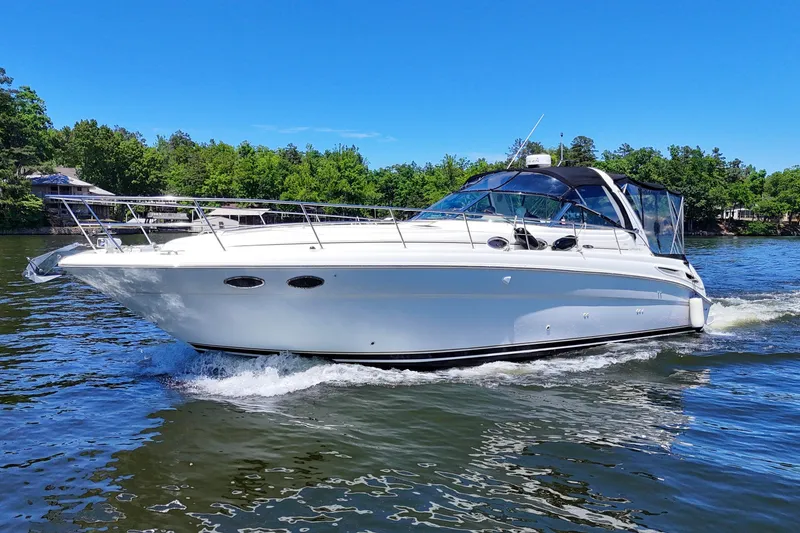 Slide: The Image of 2003 Sea Ray 380 Sundancer cruising on a serene lake under a clear blue sky. - 12
