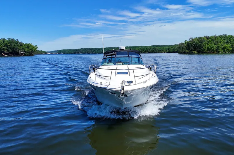 Slide: The Image of 2003 Sea Ray 380 Sundancer cruising on a scenic lake under a clear blue sky. - 13
