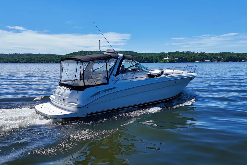 Slide: The Image of 2003 Sea Ray 380 Sundancer cruising on a serene lake under a clear blue sky. - 15
