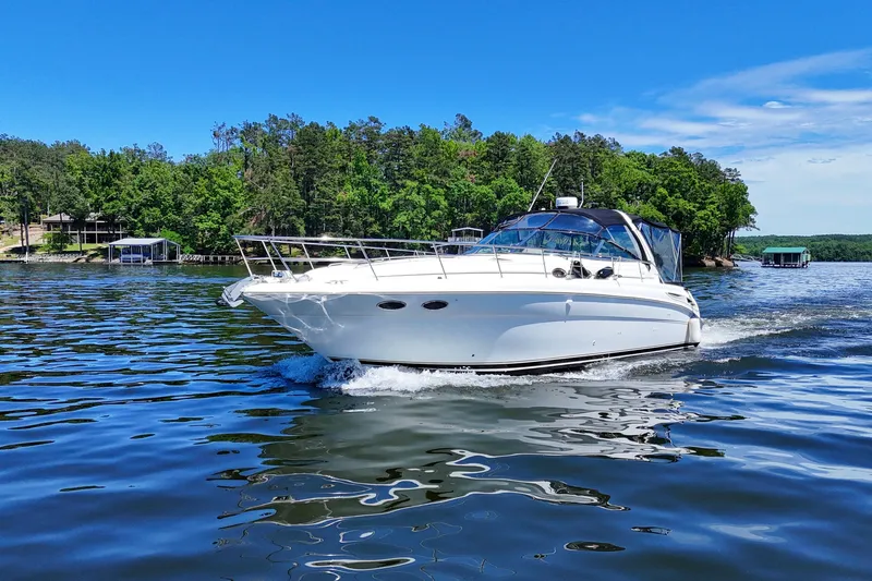 Slide: The Image of 2003 Sea Ray 380 Sundancer cruising on a scenic lake with lush green shoreline. - 16