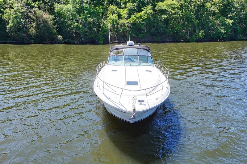 Slide: The Image of 2003 Sea Ray 380 Sundancer yacht on calm water, surrounded by lush greenery. - 2