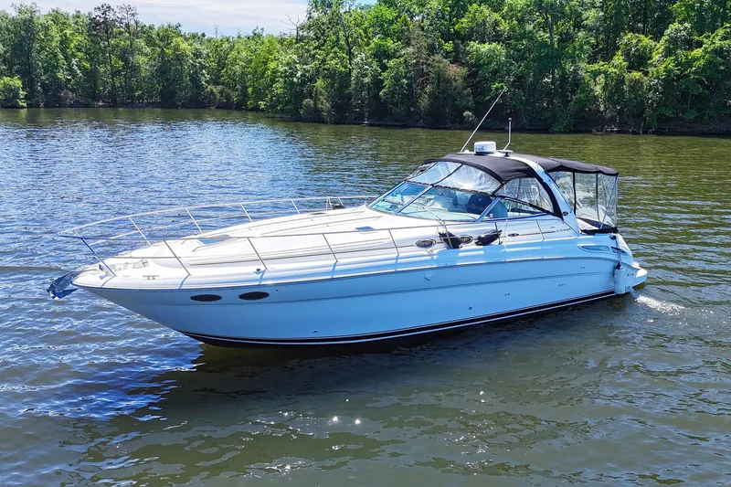 Slide: The Image of 2003 Sea Ray 380 Sundancer yacht cruising on a serene lake with lush green trees. - 4