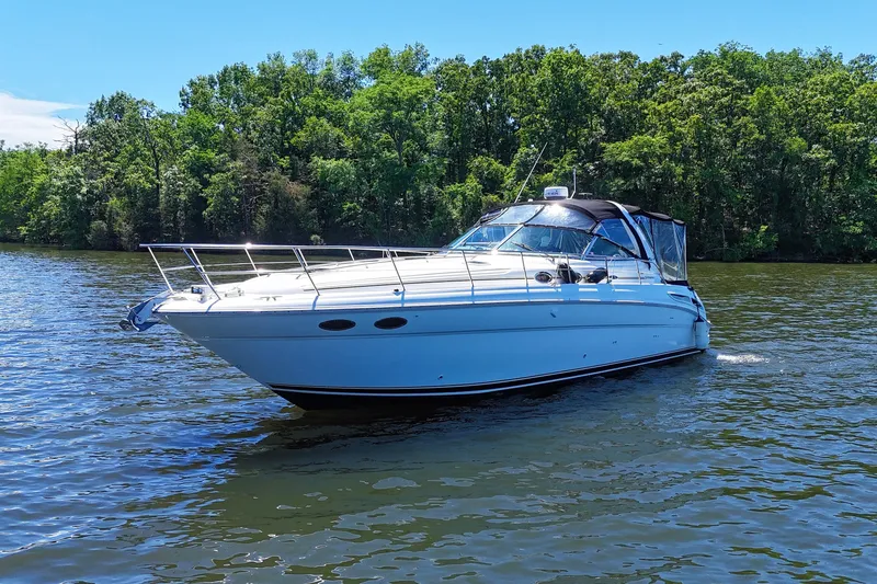 Slide: The Image of 2003 Sea Ray 380 Sundancer cruising on a serene lake with lush green trees. - 5