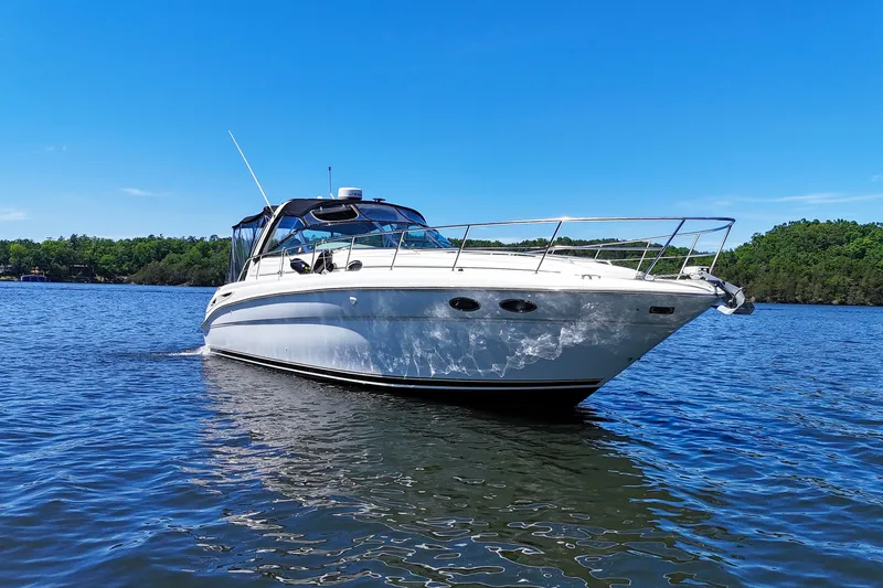 Slide: The Image of 2003 Sea Ray 380 Sundancer cruising on a serene lake under a clear blue sky. - 6