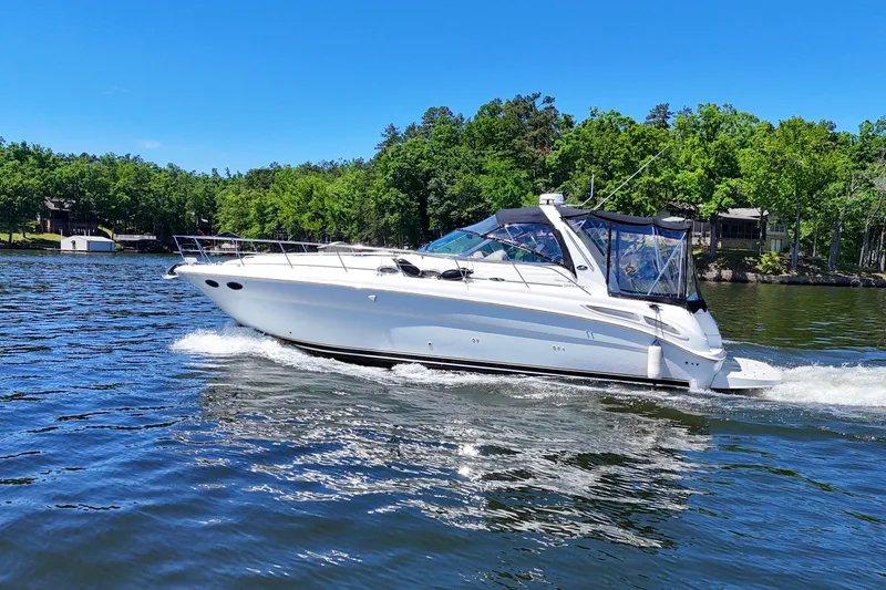 Slide: The Image of 2003 Sea Ray 380 Sundancer cruising on a scenic lake with lush green shoreline. - 7
