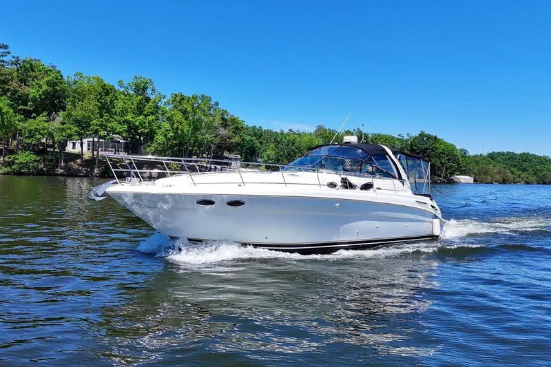 Slide: The Image of 2003 Sea Ray 380 Sundancer cruising on a scenic lake under a clear blue sky. - 8
