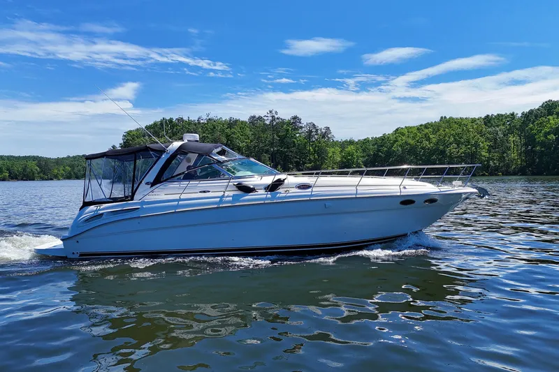 Slide: The Image of 2003 Sea Ray 380 Sundancer cruising on a serene lake under a clear blue sky. - 9