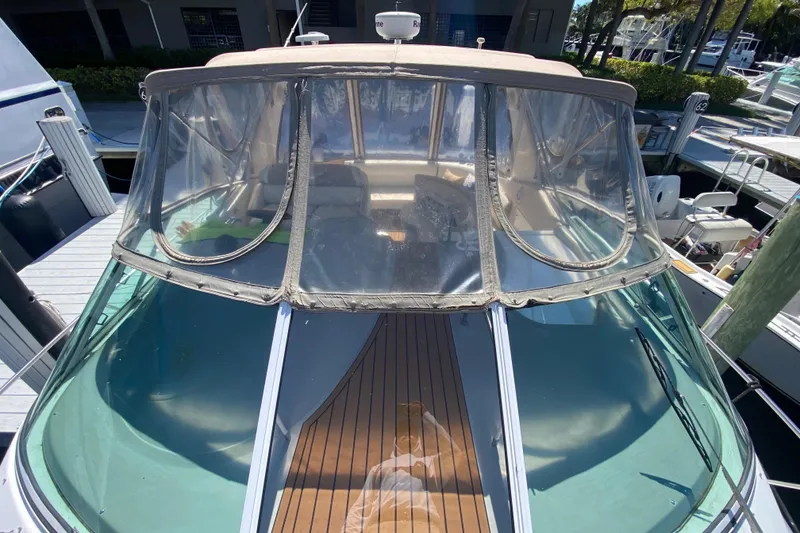 Slide: The Image of 2002 Cruisers Yachts 3572 Express with clear canopy and wooden deck, docked at marina. - 13