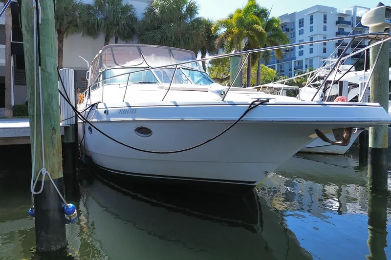 Slide: The Image of 2002 Cruisers Yachts 3572 Express docked near palm trees and modern buildings. - 3