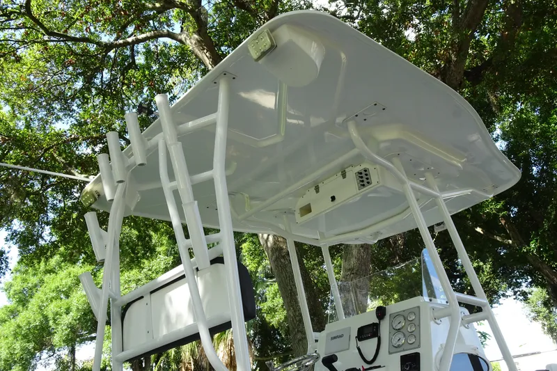 Slide: The Image of 2021 Clearwater 2200 Center Console boat with T-top and control panel, under trees. - 16