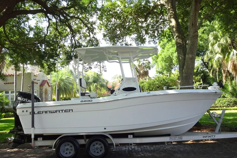 Slide: The Image of 2021 Clearwater 2200 Center Console boat on trailer, parked under trees. - 20
