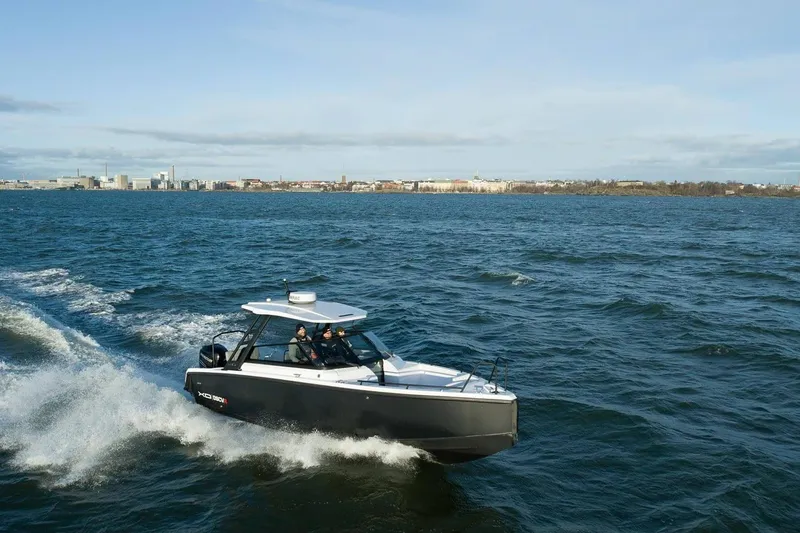 Slide: The Image of 2027 XO DSCVR 9 T-TOP boat cruising on open water near city skyline. - 10