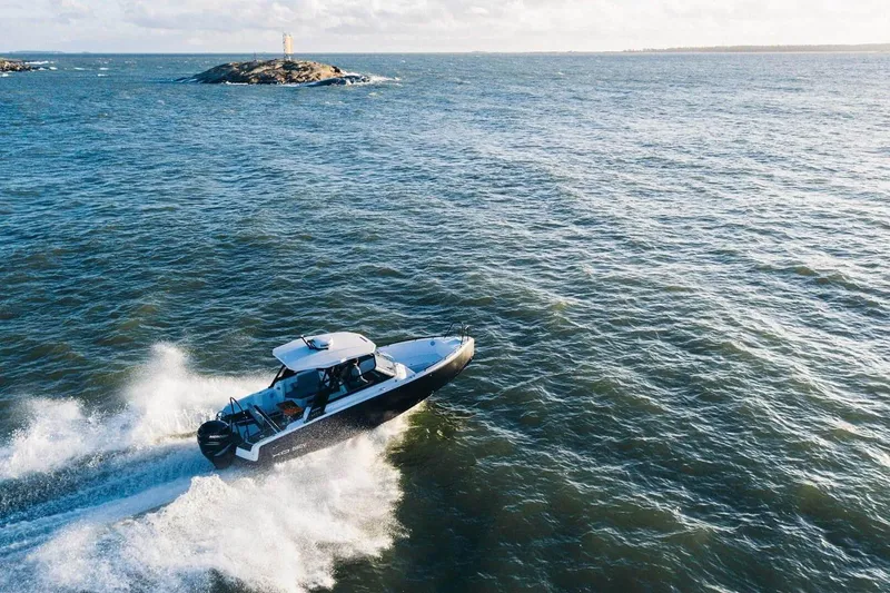 Slide: The Image of 2027 XO DSCVR 9 T-TOP boat cruising on open sea near rocky island. - 11