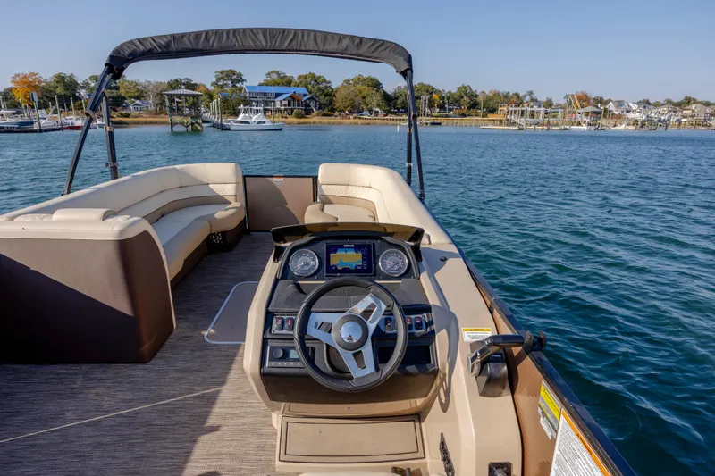 Slide: The Image of 2022 Godfrey Monaco 255 SFL pontoon boat interior with steering console on calm water. - 17