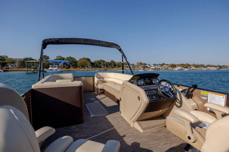 Slide: The Image of 2022 Godfrey Monaco 255 SFL pontoon boat interior with steering console, on a sunny lake. - 18
