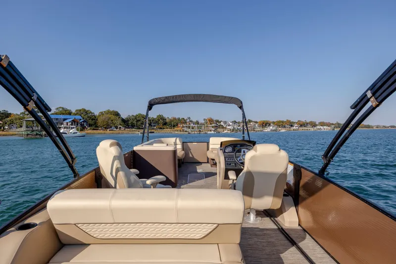 Slide: The Image of 2022 Godfrey Monaco 255 SFL pontoon boat on serene water with scenic shoreline view. - 20