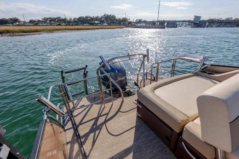 Slide: The Image of 2022 Godfrey Monaco 255 SFL pontoon boat on water, featuring comfortable seating and outboard motor. - 21