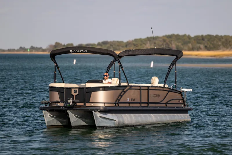 Slide: The Image of 2022 Godfrey Monaco 255 SFL pontoon boat cruising on a serene lake. - 3