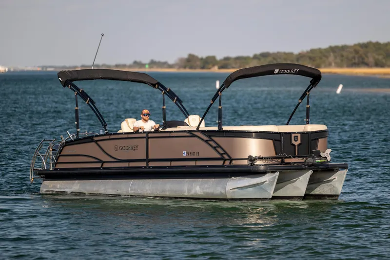 Slide: The Image of 2022 Godfrey Monaco 255 SFL pontoon boat cruising on a serene lake. - 6
